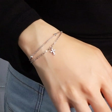 Detail of silver double-layer bracelet with moonstone heart and cross charm on wrist