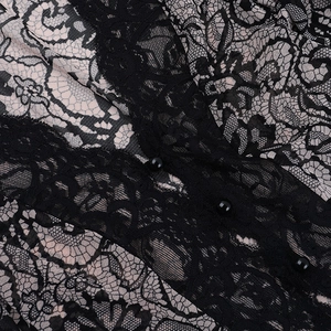 Macro shot of intricate black lace floral patterns with round buttons and nude lining