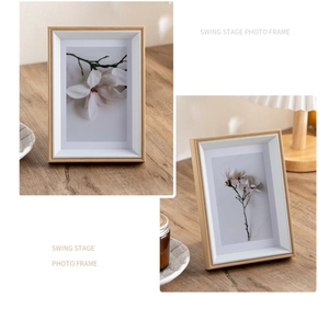 Detail of wooden photo frame with white beveled matting and floral art on a desk