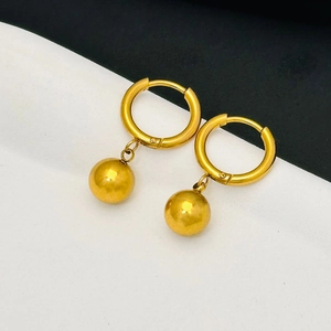 Close-up of minimalist gold-plated stainless steel ball earrings on a diagonal background