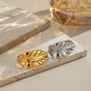 Minimalist feather leaf open rings in gold and silver finish on marble surface