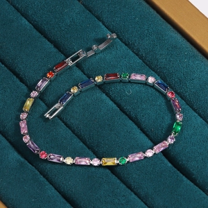 Detail of a silver-toned bracelet with multi-colored rainbow stones on green velvet fabric