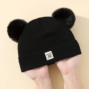 Dettaglio cappello in maglia nera per neonato con doppio pompon ed etichetta Moonlight
