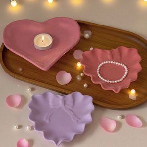 Three heart-shaped resin jewelry trays with bow relief and elegant wavy edges