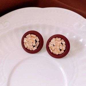 Détail de boucles d'oreilles rondes rouges avec plaquage or et cristaux scintillants