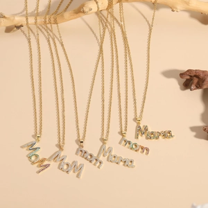 Detail of gold chain necklaces with colorful zircon encrusted MOM and MAMA letter pendants