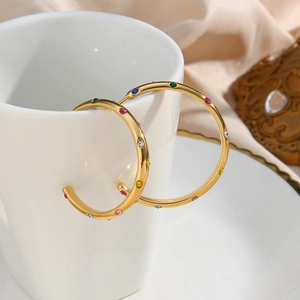 Macro shot of 18K gold plated hoop earrings featuring multi-color zircon inlay on white cup