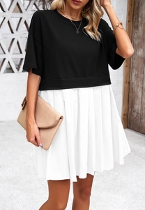 Dettaglio di un top nero a girocollo con gonna a pieghe bianca e pochette beige chic