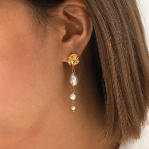 Detail of gold drop earrings with zircon chain and irregular pearls on a female model