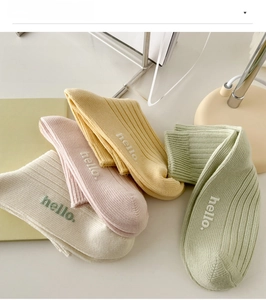 Close-up of four macaron colored cotton socks with hello embroidery and ribbed texture