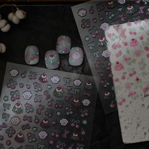 Close-up of 3D embossed nail stickers with cat paw and cherry designs on clear nails