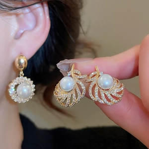 Close-up of 18k gold plated pearl drop earring featuring a crystal encrusted spiral frame