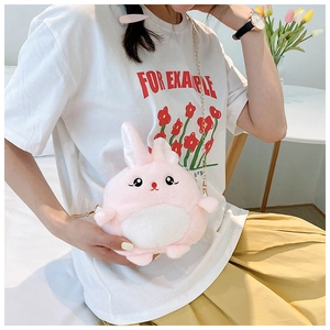 Pink plush rabbit crossbody bag with golden chain strap worn by a model in a casual setting