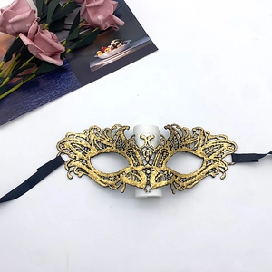 Close-up of golden lace masquerade mask showing intricate embroidery and black ribbon ties
