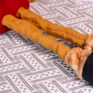 Macro detail of plush yellow telescopic legs with faux fur boots on Christmas doll