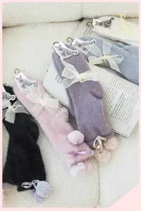 Detail of plush winter socks with lace mesh bows and decorative fur balls in four colors