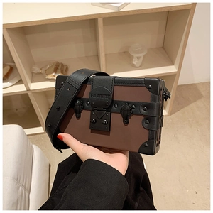 Detail of box-shaped shoulder bag with brown patchwork, rivets and metal buckle