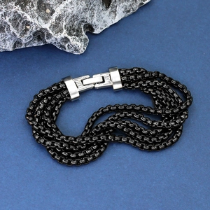 Multilayer black metal ring chain bracelet with silver clasp on textured stone background