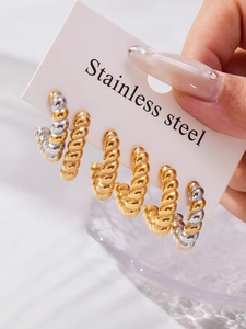 Macro detail of twisted texture stainless steel hoop earrings in gold and silver finish