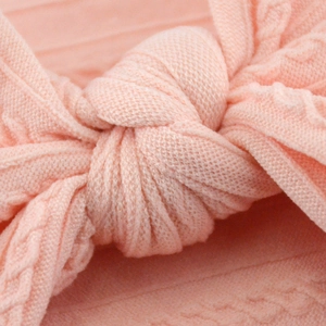 Close-up of pink knit baby headband showing the soft texture and detailed knot design