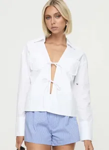Détail de chemise blanche en coton avec décolleté en V profond et double fermeture à nouer