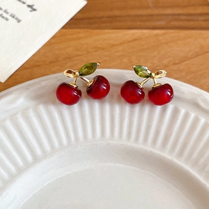 Detailed close-up of cherry stud earrings with red resin fruit and green gems