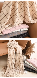 Close-up of stacked plaid scarves with tassels and soft wool texture detail