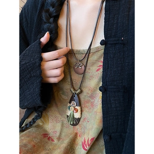 Detailed view of bohemian water-drop necklace with bow, button, and tassel accents
