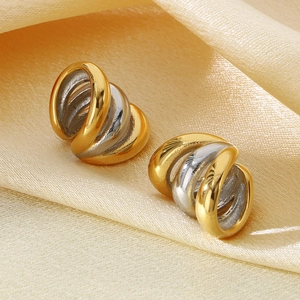 Detail of two-tone 18K gold-plated heart earrings on champagne silk background