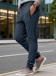 Men's navy jogger pants featuring side zipper pockets and drawstring waist in a street setting
