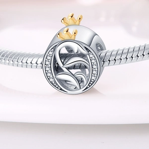 Macro shot of silver bead featuring a small gold crown and sparkling crystal accents