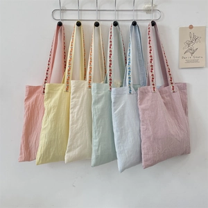 Detail showing various colors of canvas tote bags with delicate floral embroidered straps