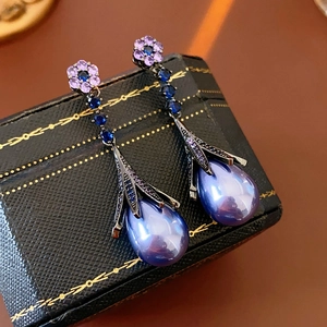 Macro view of purple flower earrings with blue crystal chains and teardrop pearls