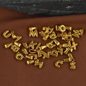 Close-up of DIY 18K gold plated stainless steel bubble letter charms on fabric background