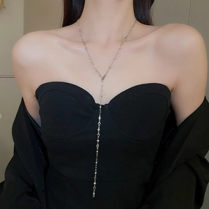 Close-up of elegant silver Y-shaped tassel necklace with heart charms on model