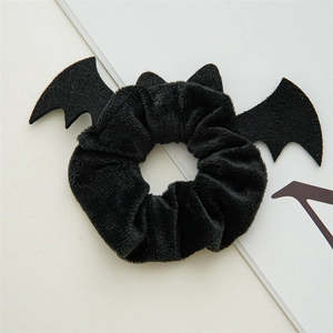 Detail of a black velvet Halloween scrunchie with bat wings on a white background