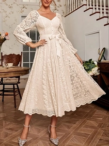 Détail de la robe vintage en dentelle blanche avec col en V, nœud à la taille et manches rétro