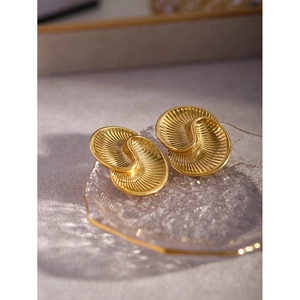 Macro shot of 18k gold stainless steel earrings with spiral texture on glass plate
