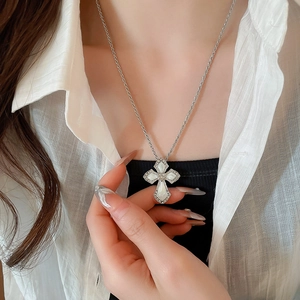 Detailed view of silver cross pendant with white inlay on twisted rope chain