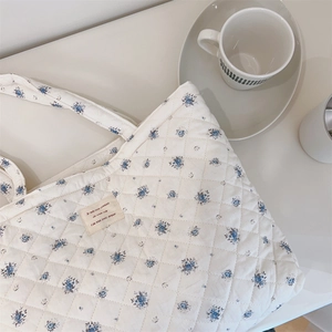 Vue détaillée du sac fourre-tout fleuri matelassé avec texture coton et étiquette
