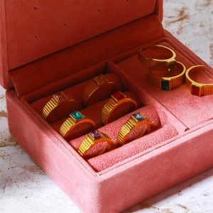 Pink velvet jewelry box displaying multiple gold stainless steel birthstone rings