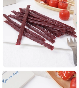 Macro shot of dark red twisted gummy strips on a cozy tabletop with lifestyle props