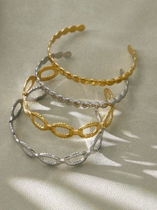 Détail de quatre joncs géométriques empilables en or 18 carats et argent avec zircons