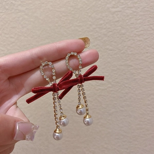 Detail of red velvet bow earrings with gold tassels, rhinestones and pearls