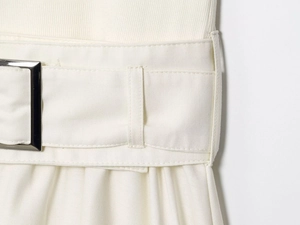 Detail of white dress fabric showing twill texture and belt with silver buckle