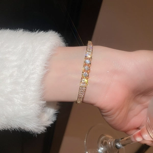 Close-up of gold plated hollow bangle featuring micro-pave zircons and round crystal clusters