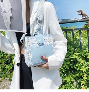 Close-up of light blue tweed bucket bag with leather trim and LOVE print strap