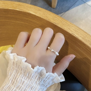 Detail of S925 silver heart charm ring with baroque pearls worn on a female finger