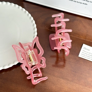 Elegant pink tortoiseshell butterfly hair claw clips on a natural wood and ceramic setting