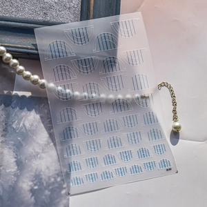 Detail of French D nail art stencil with blue stripe patterns on elegant wooden background